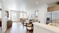 This single-floor residence offers a thoughtfully designed layout across two bedrooms and two bathrooms. The open-concept living, dining, and kitchen area forms the heart of the home, where wood-look flooring, neutral walls, and abundant natural light from large windows create a bright, welcoming atmosphere. A ceiling fan adds to the comfort of the living room, which connects seamlessly to the dining area and kitchen.

The kitchen is equipped with stainless steel appliances, light wood cabinetry extending to the ceiling, white quartz countertops, and a peninsula with bar seating — ideal for casual dining or food preparation. Recessed lighting enhances the clean, modern aesthetic.

Both bedrooms feature ceiling fans, large windows with sheer curtains, and bold blue accent walls that lend a stylish, contemporary character. The generously sized primary bedroom includes a walk-in closet outfitted with multi-tiered shelving and hanging rods. The primary bathroom offers a dual-sink vanity with wood-toned cabinetry, white countertops, and a large mirror. A hallway connects the bedrooms and bathrooms, maintaining a practical and efficient flow throughout the residence.