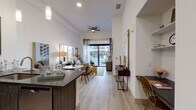 Located at 1652 Raleigh St in Denver's vibrant 80204 neighborhood, this single-floor residence offers a thoughtfully designed open-concept layout with clean contemporary finishes. Light wood-style flooring flows throughout the main living areas, complemented by crisp white walls and recessed lighting that create a bright, welcoming atmosphere.

The kitchen is a standout feature, outfitted with dark wood cabinetry, dark stone countertops, and a full suite of stainless steel appliances including a gas range, built-in microwave, and French door refrigerator. A peninsula with bar seating and pendant lighting above connects the kitchen seamlessly to the dining and living areas, making it ideal for entertaining.

The living room is generously proportioned, featuring a ceiling fan and large sliding glass doors that open to a private balcony, allowing abundant natural light to fill the space. The bedrooms offer a calm retreat, each with large windows dressed in sheer and blackout layered curtains, providing views of the surrounding community. The primary bedroom includes an en-suite bathroom with dark wood vanity cabinetry, tile flooring, and access to a walk-in closet. A dedicated laundry area with a full-size washer and dryer adds everyday convenience to this well-appointed residence.