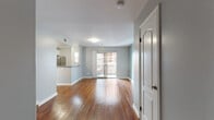 Situated along the iconic Hollywood Boulevard in Los Angeles, this single-floor unit offers a clean, modern aesthetic throughout. Rich hardwood flooring extends seamlessly across every room, providing warmth and continuity to the interior. The open-plan living area is bright and welcoming, benefiting from natural light that filters in through a sliding glass door leading to a private balcony — an ideal spot to take in the surrounding urban views.

The kitchen is positioned adjacent to the living space and features white cabinetry, granite countertops, and stainless steel appliances including a gas range with oven and overhead microwave, making it both functional and visually appealing. A breakfast bar separates the kitchen from the living area, creating a natural flow between the two spaces.

The bedroom is generously sized, finished with the same hardwood flooring, and includes a closet. A window allows natural light to filter in, while a separate sliding door in an adjoining area opens to the balcony, adding outdoor accessibility. Multiple closet doors are visible along one wall, providing ample storage.

The bathroom is neatly appointed with a white vanity, tiled shower surround, and hardwood flooring that maintains the cohesive design of the unit. Clean, light grey walls throughout lend the space a calm, contemporary feel.