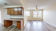 Located at 1300 Cherry St in Vicksburg, Mississippi, this two-bedroom, one-bathroom residence offers a practical and well-appointed single-floor layout. The open-concept kitchen and living area serves as the heart of the home, featuring wood-look plank flooring, warm neutral walls, and a ceiling fan that enhances air circulation. Large windows fitted with blinds allow abundant natural light to fill the living space, creating a bright and welcoming atmosphere.

The kitchen is well-equipped with warm-toned wood cabinetry, granite-style countertops, and a full suite of stainless steel appliances including a dishwasher, microwave, and electric range. A peninsula counter extends into the living area, providing additional prep and serving space.

The two bedrooms are finished with plush carpeting and feature generously sized windows that bring in natural light and views of the surrounding neighborhood. The primary bedroom includes a ceiling fan and closet access.

The bathroom is finished with large-format tile flooring and includes a vanity with granite-style countertops, matching wood cabinetry, a lighted mirror, and a tiled shower/tub combination. Clean white walls and coordinated fixtures give the bathroom a tidy, functional character throughout.
