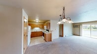 This single-floor, 2-bedroom, 2-bathroom residence offers a comfortable and functional layout with thoughtful design throughout. The open-concept kitchen and living area forms the heart of the home, featuring warm honey-toned oak cabinetry, light-colored countertops, tile flooring, and a full suite of appliances including a refrigerator, electric range, and built-in microwave. A peninsula provides a natural transition into the carpeted living area, which is accented by an elegant multi-light pendant chandelier. Baseboard heating runs throughout the residence, ensuring efficient climate control year-round.

The spacious primary bedroom is a standout feature, offering generous square footage, plush carpeting, and a sliding glass door that opens to a scenic water view. A well-organized walk-in closet with built-in shelving and hanging rods provides ample storage. The second bedroom also benefits from natural light, with dual windows framing views of the surrounding landscape. Both bathrooms are finished with tile flooring, oak vanity cabinetry, and light countertops; one includes a tub-shower combination, and the other features a walk-in shower. A dedicated utility room and additional closet round out the practical amenities of this well-designed home.
