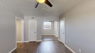 This efficiently designed 2-bedroom, 1-bathroom single-floor home offers a cohesive, modern aesthetic throughout. Dark hardwood-style flooring runs continuously across all rooms, providing a warm yet contemporary foundation that contrasts beautifully with the cool gray walls and crisp white trim.

The living area features a ceiling fan with light fixture, a textured ceiling, and an elegant arched passageway that connects rooms and adds architectural character. The kitchen is well-equipped with white shaker-style cabinetry, marble-look quartz countertops, a subway tile backsplash, a stainless steel sink, and stainless steel appliances including a refrigerator and electric range.

The spacious primary bedroom offers ample room and is served by a louvered-door closet, while the second bedroom benefits from a large window that invites natural light and outdoor views. Both rooms feature the same consistent flooring and neutral gray paint palette.

The bathroom is clean and functional, finished with white subway tile surrounding a full soaking tub and shower combination, with a window providing natural light and ventilation. A dedicated entrance and hallway provide a practical transition into the home. Overall, the space presents a fresh, updated interior with consistent finishes throughout.