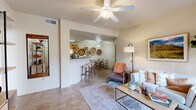 This single-story, 2-bedroom, 1-bathroom residence offers a smartly organized floor plan that maximizes functionality across its well-proportioned footprint. The living room serves as the central hub of the home, featuring tile flooring, a ceiling fan, and a seamless visual connection to both the dining area and kitchen via an open-concept pass-through design. Warm, neutral tones carried throughout create a cohesive and inviting ambiance.

The kitchen is equipped with honey-toned wood cabinetry, white appliances including a range, microwave, refrigerator, and dishwasher, and a breakfast bar with barstool seating. Notably, an in-unit laundry area with full-sized washer and dryer is integrated directly off the kitchen, alongside a pantry closet providing additional storage.

The primary bedroom is generously sized and includes a ceiling fan, natural light from a window, and access to a dedicated walk-in closet with built-in shelving and hanging rods. The second bedroom is equally bright with similar features. The shared bathroom offers a full tub-shower combination with tile surround. Two closets throughout the unit further enhance storage capacity.