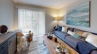 This single-floor residence offers a thoughtfully designed open-concept layout that balances comfort and functionality. The living room serves as the heart of the space, featuring warm hardwood-style flooring, a large sliding glass door with vertical blinds that flood the room with natural light and provide access to an outdoor area, and ample space for relaxed seating arrangements.

The kitchen is both practical and attractive, showcasing white shaker-style cabinetry, light countertops with a peninsula for additional prep and seating space, and stainless appliances including a refrigerator and electric range. The wood-look flooring carries through seamlessly, and a dedicated laundry area with a full-size washer and dryer is conveniently accessible from the kitchen corridor.

The bedrooms are carpeted for comfort and feature neutral wall tones, natural light from well-positioned windows with blinds, and generous proportions suited for queen or king-sized furniture. The bathroom is finished with wood-look vinyl flooring, white cabinetry with a wide vanity and light countertop, and a full tub-shower combination. Throughout the space, a consistent neutral palette and modern fixtures create a clean, cohesive aesthetic that is both inviting and move-in ready.