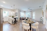 Located at 1387 East Vine Street in Kissimmee, Florida, this single-floor, 2-bedroom, 1-bathroom residence offers a thoughtfully designed layout with contemporary finishes throughout. A welcoming entrance hallway, adorned with vibrant artwork and warm wood-look flooring, sets the tone for the rest of the home.

The heart of the space is a generous open-concept area combining the living room, dining room, and kitchen. The kitchen features crisp white shaker cabinetry, stainless steel appliances, quartz countertops, a tile backsplash, and a breakfast bar with pendant lighting overhead. The adjacent dining area flows seamlessly into the bright living room, which is filled with natural light from large windows and equipped with a ceiling fan.

Both bedrooms are comfortably sized, with the primary bedroom offering generous proportions, hardwood-style flooring, and access to a spacious walk-in closet with built-in wire shelving. The second bedroom benefits from large windows with outdoor views. The bathroom is elegantly finished with marble-style tile flooring, a white vanity, and a glass-enclosed walk-in shower. Additional highlights include a dedicated laundry area, a utility room, and ample closet storage throughout the home.