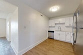 Located at 100 Seabreeze Blvd in Daytona Beach, Florida, this single-floor, 2-bedroom, 2-bathroom residence offers a clean and functional layout designed for comfortable living. Light wood-style flooring flows consistently throughout, complementing the bright white walls and textured ceilings that give the space an airy, fresh feel.

The kitchen is a standout feature, outfitted with crisp white cabinetry, a classic subway tile backsplash, a stainless steel dishwasher, a refrigerator, and a modern sink — all combining to create a practical and attractive cooking space. The adjacent living area provides an open, versatile setting with ample room for everyday use.

Both bedrooms are well-proportioned, each equipped with sliding panel closets for convenient storage. The primary bedroom offers a comfortable footprint suited for a full furniture arrangement. The two bathrooms are finished in a clean, all-white palette — one featuring a full tub-shower combination with tiled surround, and the other with a compact vanity accented by warm gold fixtures and partial tile walling.

A dedicated laundry area with hookups adds to the home's practical appeal. The unit's consistent, neutral finishes throughout make for a move-in-ready space in a sought-after Daytona Beach location.