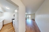 Located at 985 Monte Bello Dr in Gilroy, CA, this 2-bedroom, 1-bathroom residence offers a clean, bright, and efficiently designed single-floor layout. Warm hardwood-style flooring flows consistently throughout the entire space, tying each room together cohesively.

The living room is a comfortable, open area bathed in natural light from sliding glass doors that lead to a private balcony, offering outdoor views of the surrounding neighborhood. A wall-mounted climate control unit provides year-round comfort.

The galley-style kitchen is well-appointed with white cabinetry, light stone countertops, and stainless steel appliances including a refrigerator, electric range, and over-the-range microwave. The efficient layout maximizes counter and storage space.

A connecting hallway with arched doorways leads to both bedrooms. The primary bedroom is generously sized, offering ample room for furnishings. The second bedroom features a window with a view of lush greenery, a baseboard heater, and its own natural light. The shared bathroom is finished in a clean, all-white palette with a vanity, white cabinetry, and wood-tone flooring. The entire space maintains a fresh, move-in-ready aesthetic with crisp white walls throughout.