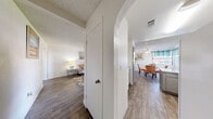 Located in Las Vegas, NV, this single-floor residence offers two bedrooms, three bathrooms, and a thoughtfully arranged layout. The living room features wood-look flooring, a large sliding glass door with views to the outdoors, and an open sightline into the adjacent dining area, creating a cohesive and welcoming common space. The dining room is accented by a ceiling fan, a window dressed with teal curtains, and the same wood-look flooring that flows throughout the main areas. The kitchen is well-appointed with gray cabinetry, granite-style countertops, white appliances, and a peninsula that provides additional prep space. A charming arched doorway connects the kitchen to the hallway, adding an architectural detail that repeats throughout the home. The primary bedroom is generously sized with plush carpet flooring, while the second bedroom also features carpet and a built-in closet. Bathrooms are finished with gray vanities, granite-style countertops, and soaking tubs framed by arched surrounds. Two hallways connect the spaces efficiently, and a dedicated closet adds practical storage. The textured ceilings are consistent throughout, giving the home a uniform, finished appearance.