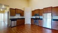 Located at 4557 Tundra Ln in Madison, Wisconsin, this single-floor unit offers a thoughtfully designed layout with notable architectural features throughout. The open living area is defined by impressively tall ceilings accented by recessed lighting and a ceiling fan, creating an airy, expansive atmosphere. Rich hardwood-style flooring runs throughout the main living spaces, adding warmth and continuity.

The kitchen is a standout feature, offering generous cabinetry in warm wood tones with crown molding details, dark granite-style countertops, and a full suite of stainless steel appliances including a refrigerator, electric range, built-in microwave, and dishwasher. The wraparound cabinet layout maximizes storage and counter workspace.

The bedroom is carpeted for comfort and equipped with a wall-mounted mini-split HVAC unit, providing independent climate control. Natural light enters through a window fitted with blinds.

Two bathrooms serve the unit. One features a tiled walk-in shower with decorative mosaic accents and earthy stone-look tile flooring. The second includes a soaking tub, dark granite vanity with wood cabinetry, and matching tile flooring. Both bathrooms maintain a consistent, refined aesthetic throughout.
