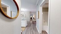 This single-story residence offers a thoughtfully designed layout with a cohesive neutral color palette and wood-look flooring that flows throughout the main living areas. The entryway opens to a central hallway connecting the key spaces, with a bathroom conveniently accessible from the corridor.

The kitchen is outfitted with white shaker-style cabinetry, granite-look countertops, a double sink, and black appliances including a range, microwave, and dishwasher. An adjacent dining area features crown molding, a chandelier, and a built-in shelf, lending a refined character to everyday meals.

The living room is bright and welcoming, with a ceiling fan, crown molding, and a glass door that opens to a private outdoor patio. Natural light filters in through window treatments, creating a comfortable atmosphere.

Both bedrooms feature plush carpeting, generous windows with outdoor views, and ceiling fans. The primary bathroom includes a soaking tub and granite-look countertops. A dedicated laundry room with side-by-side washer and dryer hookups and built-in shelving adds practical convenience to this well-rounded residence.