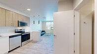 Located on Massachusetts Avenue in Amherst, MA, this efficiently designed one-bedroom, one-bathroom unit offers a modern, contemporary aesthetic throughout its single floor. Light wood-style flooring runs seamlessly across all rooms, lending a bright, cohesive feel to the entire space.

The open-concept kitchen and living area forms the heart of the unit. The kitchen is outfitted with stainless steel appliances — including a full-size refrigerator, electric range, built-in microwave, and dishwasher — complemented by light wood cabinetry, white countertops, and a stainless sink. Pendant lighting accents the kitchen area, adding a modern touch. The adjoining living room benefits from a large window that draws in natural light and provides outdoor views, creating an airy and comfortable environment.

The bedroom is a well-proportioned private retreat featuring the same light flooring and neutral wall tones, offering a calm and functional space. A built-in shelf above the bed area adds practical storage.

The bathroom is clean and contemporary, featuring a walk-in shower stall, a wood-toned vanity with white countertop, and tile flooring in a neutral palette. Recessed lighting adds a polished finish.

The entryway is thoughtfully appointed with a key-fob entry door and an accessible electrical panel, reflecting the building's modern construction and attention to practical detail.