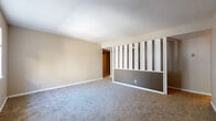 Located at 105 Lowery St in Hot Springs, Arkansas, this single-floor property offers a straightforward and functional layout throughout. The living area is a standout feature, showcasing plush carpeting and a distinctive mid-century-style decorative divider wall composed of vertical white slats over a textured dark panel — adding architectural character to the space. Textured ceilings are consistent throughout, complementing the neutral, warm-toned walls.

The bedrooms are generously sized, each featuring soft carpeting and windows that invite natural light and outdoor views of surrounding trees. One bedroom includes direct access to the full bathroom, providing added convenience. A closet is also accessible from the bathroom area, offering practical storage.

The galley-style kitchen is efficiently designed with dark wood cabinetry lining both sides, a double sink with adjacent dishwasher, electric coil range, and a refrigerator — all set on wood-look flooring that continues into the bathroom. The bathroom features a tiled tub-and-shower combination, a white vanity with storage drawers, and a large mirror.

Overall, this property presents a practical and livable floor plan with defined spaces, ample storage, and a consistent design aesthetic throughout its single level.