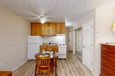 Located at 307 Thompson Street in Ann Arbor, Michigan, this one-bedroom, one-bathroom unit offers a practical and well-organized layout across a single floor. Light-toned hardwood-style flooring runs throughout, lending a clean and cohesive look to the entire space.

The combined kitchen and dining area is outfitted with warm honey-toned oak cabinetry providing ample upper storage, a white refrigerator, electric range, and a sink with under-cabinet workspace. A ceiling fan overhead aids ventilation and comfort. A compact dining table with seating fits neatly within the space, making it functional for everyday meals.

The bedroom occupies roughly half the unit and is notably bright, featuring large windows that invite generous natural light and offer leafy outdoor views. The room comfortably accommodates a bed, dresser, and desk, and benefits from two closets for additional storage.

The bathroom is efficiently designed with a tiled walk-in shower enclosed by glass sliding doors, a toilet, and a vanity with overhead cabinetry. A hallway connects the main living areas, and a wall-mounted electrical panel is conveniently accessible near the kitchen.

The unit's straightforward layout and practical finishes make it a well-suited option for individuals seeking a functional living space in Ann Arbor.