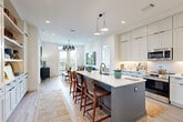 Located at 14020 Stream Way in Charlotte, NC, this well-appointed 2-bedroom, 4-bathroom residence showcases a thoughtfully designed open-concept layout with modern finishes throughout. Light hardwood flooring runs through the main living areas, and recessed lighting complements the natural light that pours in through large windows and a glass balcony door.

The kitchen is a standout feature, boasting a substantial two-toned island with a crisp white quartz countertop and a slate-blue base, paired with seating for casual dining. Floor-to-ceiling white shaker cabinets, a subway tile backsplash, stainless steel appliances, and a modern pendant chandelier complete the space. The kitchen flows seamlessly into the living area, where large windows frame outdoor views and fill the room with light.

The primary bedroom offers a tranquil retreat with plush carpeting, a ceiling fan, and large windows overlooking the balcony. Its en-suite bathroom features a glass-enclosed walk-in shower with large-format tile, mosaic tile flooring, and sleek black fixtures. The second bedroom is equally well-appointed with its own en-suite bath and dedicated closet access. Two additional closets provide ample storage throughout the residence. The overall ambiance is bright, clean, and contemporary.