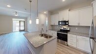 Located at 1630 Lewis Creek Dr in Wilmington, NC, this single-floor residence offers a clean, modern aesthetic throughout. The open-concept kitchen is a standout feature, showcasing white shaker cabinetry, granite countertops, a subway tile backsplash, stainless steel appliances, and a central island with a double-basin sink illuminated by sleek pendant lighting. Light wood-look flooring flows seamlessly throughout the entire space, creating a cohesive and contemporary feel.

The bedrooms are generously proportioned, each featuring neutral wall tones, ceiling fans, and large windows dressed with horizontal blinds that invite abundant natural light. Vaulted ceilings in select areas add to the overall sense of openness and volume.

The bathroom is thoughtfully designed with granite-topped white vanity cabinetry, wood-look tile flooring, and a spacious walk-in shower enclosed by sliding glass doors with brushed nickel hardware. Built-in shelving within the shower adds practical storage. Additional windows in the bathroom allow natural light to brighten the space.

Overall, the residence presents a fresh, move-in-ready interior with consistent upscale finishes, neutral tones, and well-appointed rooms that provide both comfort and functionality.