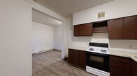 Located at 301 W Main St in downtown Spokane, Washington, this two-bedroom, one-bathroom residence offers a practical and efficiently designed layout across a single floor. Wood-style plank flooring runs throughout the unit, providing a cohesive and easy-to-maintain surface in every room.

The kitchen is equipped with dark rich-toned cabinetry offering ample upper and lower storage, light-colored countertops with a tile backsplash, a double-basin sink, a coil-top electric range with oven, and a full-size refrigerator. The kitchen opens directly toward the dining area, supporting an easy flow for daily living.

Both bedrooms are bright, white-walled spaces with wood-style flooring and baseboard heating. The primary bedroom includes a closet with a hanging rod and shelf for organized storage, while a window in the secondary bedroom allows for natural light. A connecting hallway links the rooms efficiently.

The full bathroom features a soaking tub with a tiled surround, a vanity with a sink, and wood-style flooring, maintaining a clean and functional aesthetic. Baseboard heating is present throughout the unit, ensuring consistent warmth. The overall layout is straightforward and practical, well-suited for comfortable urban living in the heart of Spokane.