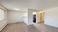 Located in Lakeville, MN, this two-bedroom, one-bathroom residence offers a well-organized single-floor layout designed for comfortable everyday living. The open-concept living and dining area is anchored by durable luxury vinyl plank flooring in a neutral gray tone, textured ceilings, and baseboard heating. Multiple windows bring in natural light and provide views of the surrounding neighborhood. The kitchen features a peninsula with a warm wood-tone countertop that separates it from the living space, white upper cabinetry, a tile backsplash, and black appliances, including a range and refrigerator, all illuminated by a flush-mount ceiling light. Both bedrooms are carpeted and offer a cozy, quiet atmosphere, each with natural light from windows fitted with blinds and wood-tone frames. The bedrooms are served by generously sized sliding-door closets, providing practical storage. Additional closets throughout the unit further enhance storage capacity. The full bathroom includes a tub-shower combination, vanity with cabinetry, and LVP flooring that ties into the rest of the home. The neutral color palette and clean finishes throughout give the space a move-in ready feel suited for a variety of lifestyles.