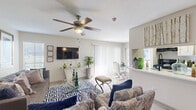 This single-floor residence offers a thoughtfully designed layout that balances comfort and functionality throughout. The living room serves as the heart of the home, showcasing wood-look flooring, a ceiling fan with light fixture, and an abundance of natural light streaming through large windows and sliding glass doors. A bold navy-and-white geometric area rug anchors the seating arrangement, which flows seamlessly into a dedicated dining area equipped with a sleek table and modern chairs. The open sightlines between these spaces create an inviting, airy atmosphere ideal for both relaxing and entertaining.

The galley-style kitchen is efficiently organized with white cabinetry, light countertops, a deep stainless steel sink, and black appliances including a range, dishwasher, and refrigerator. A patterned area rug and tile backsplash add texture and character to the space.

The bedroom is a serene retreat, featuring plush carpeting, a ceiling fan, ample natural light from a window with blinds, and generous wall space for décor. The full bathroom offers a tiled shower-tub combination, wood-look flooring, and neutral wall tones that create a clean, calm environment.

Completing the home is a dedicated laundry room with side-by-side washer and dryer units and built-in shelving for additional storage.