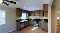 This two-story home is designed with both functionality and style in mind. The kitchen serves as a standout feature, showcasing rich, warm-toned wood cabinetry with raised-panel detailing that extends to the ceiling, maximizing storage throughout. Dark granite countertops provide a striking contrast against the cabinetry, lending the space a polished, refined look. Stainless steel appliances, including a gas range and dishwasher, add a modern, professional touch to the cooking area. The kitchen is laid out in an efficient L-shape configuration, offering ample counter space for meal preparation. A window above the sink allows natural light to flow in, brightening the space during the day. Recessed lighting in the ceiling further ensures the kitchen is well-illuminated at all times. The tile flooring is both practical and visually cohesive, complementing the overall warm color palette of the room. Display cabinetry with glass inserts adds an elegant finishing touch, ideal for showcasing decorative items. Spanning two floors, this home offers versatile living across multiple levels, providing generous space for everyday living and entertaining alike.
