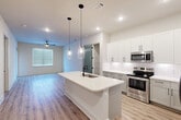 Located in Spring, TX, this well-appointed 2-bedroom, 2-bathroom single-story home offers a clean, modern aesthetic with thoughtful design details throughout. The open-concept living and kitchen area serves as the heart of the home, anchored by a sleek center island with a white quartz countertop, an undermount sink, and stylish pendant lighting overhead. The kitchen is equipped with stainless steel appliances — including a range, microwave, and refrigerator — complemented by crisp white upper cabinetry, gray lower cabinets, and a classic white subway tile backsplash. A dedicated pantry with shelving provides generous storage. Light wood-style flooring flows consistently throughout the home, creating a cohesive and airy feel. The living area features a ceiling fan and a window that allows natural light to fill the space. Both bedrooms are comfortably sized, each with windows fitted with blinds and ceiling fans for comfort. The primary bedroom offers a generous footprint with its own closet. The bathrooms are finished in a modern style, one featuring a soaking tub with gray tile surround, white vanity cabinetry, and dark hardware accents. Three closets in total provide ample storage across the home.