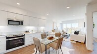 Located at 1011-1013 Everett St in the vibrant Echo Park neighborhood of Los Angeles, this thoughtfully designed one-bedroom, one-bathroom unit offers a clean, modern aesthetic throughout. The open-concept layout seamlessly connects the kitchen, dining, and living areas, creating a bright and functional living space bathed in natural light. Wide-plank wood-style flooring runs throughout, adding warmth to the crisp white palette.

The kitchen is outfitted with sleek white cabinetry extending to the ceiling, white quartz countertops, and a full suite of stainless steel appliances, including a refrigerator, range, microwave, and dishwasher. A dedicated dining area with a glass-top table sits adjacent, ideal for everyday meals or entertaining.

The living room opens directly onto a private balcony through a sliding glass door, offering treetop and neighborhood views of Los Angeles. The bedroom is comfortably sized, featuring a large window with outdoor views, and includes a closet with built-in shelving. The bathroom features warm wood-toned cabinetry, a single vanity with a wide mirror, and a full tub-shower combination with marble-style tile surround. Recessed lighting throughout completes the polished, contemporary feel of this well-appointed unit.