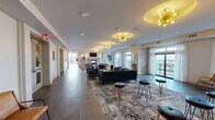 Located in the vibrant Heights Waterworks community in Houston, TX 77008, this single-floor amenity space is a masterclass in contemporary design and thoughtful functionality. The entrance welcomes visitors with large-format tile flooring, curated wall art, and glass-panel doors that offer a preview of the sophisticated interior beyond.

The expansive lounge area serves as the heart of the space, furnished with plush velvet seating, patterned area rugs, and gold-accented bar stools. A striking sputnik-style chandelier anchors the ceiling, casting warm light across the room. A marble-surround fireplace with a mounted flat-screen TV creates an intimate focal point, flanked by sconce lighting and vibrant abstract artwork.

A dedicated wet bar features a mirrored herringbone tile backsplash, granite countertops, a wine refrigerator, and built-in cabinetry — ideal for entertaining. Adjacent, the full catering kitchen is outfitted with stainless steel appliances including a wall oven, microwave, dishwasher, and refrigerator, complemented by reflective subway tile and warm terracotta-toned floor tiles.

Floor-to-ceiling windows and glass doors along the perimeter flood the space with natural light and provide access to an outdoor balcony, enhancing the open, airy ambiance throughout.