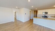 Located at 5076 Branch Point Dr in Valdosta, Georgia, this single-story home presents a clean, modern interior with a cohesive neutral color palette throughout. The flooring is consistent warm-toned wood-look planks that run seamlessly across all living areas, lending a sense of continuity and spaciousness to the layout.

The open-concept living and kitchen area serves as the heart of the home. The kitchen is outfitted with white cabinetry, granite countertops, stainless steel appliances including a refrigerator and range, and a peninsula island that provides additional prep space and casual seating. A walk-in pantry with wire shelving is conveniently accessible directly from the kitchen. Recessed lighting illuminates the space effectively throughout.

A central hallway connects the main living areas to the private rooms, with multiple doors leading to well-proportioned bedrooms, each featuring natural light from windows with blinds. The bathroom includes granite countertops, white cabinetry, a large mirror, and a walk-in shower.

Additional storage is provided through a spacious walk-in closet with wire shelving systems. The attached garage houses the water heater and electrical panel, and offers generous space for vehicles or additional storage.