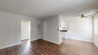 Located at 4901 Clair Del Ave in Long Beach, CA, this single-story 1-bedroom, 2-bathroom unit offers a well-organized layout across a compact yet efficiently designed floor plan. The living and dining areas share an open, connected space finished with rich dark hardwood-style flooring and neutral gray walls, creating a clean and modern aesthetic. Textured ceilings and recessed HVAC vents are found throughout. The galley-style kitchen is thoughtfully equipped with white shaker cabinetry, dark countertops, stainless steel appliances including a gas range and refrigerator, and a dual-basin sink beneath overhead lighting. The bedroom features plush wall-to-wall carpeting, a sliding glass door that opens to a private enclosed patio, and a dedicated closet. The patio itself is a fenced outdoor space with a painted concrete floor and decorative mulch landscaping—ideal for outdoor relaxation. Two full bathrooms serve the unit; one includes a wide vanity with ample cabinet storage and a large mirror, while the other offers a clean tub-shower combo. Two closets provide additional storage throughout the home. This unit combines practical design with comfortable livability in a Southern California setting.