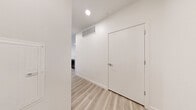 This thoughtfully designed 1-bedroom, 1-bathroom residence offers a clean, modern aesthetic throughout its well-organized single-floor layout. Light-toned hardwood-style flooring runs through the entryway, living room, and kitchen, creating a bright and cohesive feel from the moment you enter the hallway.

The open-concept kitchen is a standout feature, showcasing a two-toned cabinetry design with crisp white upper cabinets and dark lower cabinets, complemented by a gray tile backsplash, quartz countertops, a peninsula with sink, and a full suite of stainless steel appliances. The living area is generously sized with recessed lighting and a neutral palette that maximizes the sense of openness.

The bedroom is carpeted for comfort and features a ceiling fan, a window with exterior views, and direct access to a private balcony — an ideal retreat for fresh air and outdoor enjoyment. Two closets, including a walk-in with built-in shelving and hanging rods, provide ample storage.

The bathroom continues the modern design language with a sleek dark vanity, white quartz countertop, undermount sink, chrome fixtures, and a large mirror with integrated cabinetry. An in-unit laundry area adds everyday convenience, rounding out this well-appointed and move-in-ready residence.
