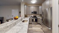 Located at 70 Oak St in Rochelle Park, NJ, this 2-bedroom, 2-bathroom residence offers a thoughtfully designed single-floor layout with contemporary finishes throughout. Wood-style plank flooring flows seamlessly across all living areas, lending a warm, cohesive aesthetic to the entire space.

The open living and dining area is bright and inviting, featuring a ceiling fan and sliding glass doors that lead to a private balcony, allowing natural light to fill the room. The adjacent kitchen is well-appointed with granite countertops, gray shaker-style cabinetry, stainless steel appliances including a gas range, microwave, and refrigerator, and an extended breakfast bar — ideal for both everyday cooking and entertaining.

Both bedrooms are generously sized, each featuring ceiling fans, wood-style flooring, and large windows with blinds that bring in natural light. The primary bedroom includes ample closet space, while the second bedroom offers a roomy closet and a bright window with outdoor views.

The two bathrooms are finished with dark wood vanities, white countertops, and wood-style flooring. The primary bath features a sleek walk-in glass shower, while the second bath offers a full soaking tub and shower combination, along with a built-in linen closet for additional storage. Together, these elements create a practical and stylish living space.