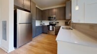 This two-floor residence offers a well-designed layout that balances functionality and comfort across both levels. The main floor features warm hardwood flooring throughout, anchored by a well-appointed kitchen with dark-toned cabinetry, light quartz countertops, stainless steel appliances, and a undermount sink. The open living area is filled with natural light from large windows that frame lush, elevated outdoor views, complemented by a staircase connecting both floors. A half bathroom on the main level includes a rich wood vanity with a granite countertop and hardwood flooring. Upstairs, the carpeted bedrooms provide a cozy retreat, each equipped with ceiling fans and generous closet space. The primary bedroom opens to a spacious walk-in closet outfitted with wire shelving systems for organized storage. The upper-level bathroom mirrors the quality of the main floor, featuring granite countertops, a wood vanity with ample drawer storage, and a large mirror. The 3D dollhouse view reveals a compact yet efficiently arranged two-story floorplan with a central staircase. Throughout the space, neutral tones, clean white walls, and consistent finishes create a cohesive and move-in-ready environment.