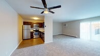 Located at 41 S Naper Blvd in Naperville, Illinois, this single-floor unit offers a functional and well-appointed layout designed for comfortable everyday living. The open-concept design connects the kitchen and living area seamlessly, creating a spacious, unified environment.

The kitchen is a standout feature, finished with rich dark wood cabinetry, granite countertops, and a classic white subway tile backsplash. A full suite of stainless steel appliances includes a gas range, over-the-range microwave, and refrigerator, complemented by hardwood flooring that adds warmth to the space.

The living area is generously proportioned, finished with neutral carpet and painted in soft gray tones that lend a calm, understated ambiance. A five-blade ceiling fan with an integrated light fixture anchors the room, while a wall-mounted air conditioning unit and baseboard heating provide year-round climate control. Natural light enters through a sliding glass door with vertical blinds.

An additional room features carpeted flooring, neutral walls, and a pass-through window to the kitchen, offering flexible use as a bedroom or secondary living space. The bathroom includes a dark wood vanity with a granite-topped sink, hardwood flooring, and a well-placed mirror above the basin, maintaining the cohesive design aesthetic carried throughout the unit.