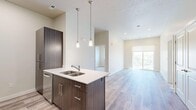 Located at 396 S State St in Orem, Utah, this well-appointed 2-bedroom, 2-bathroom unit offers a thoughtfully designed single-floor layout. The open-concept living area seamlessly connects the kitchen, dining, and living spaces, creating a bright and functional environment. The kitchen is a standout feature, equipped with stainless steel appliances including a refrigerator, range, and microwave, complemented by dark espresso cabinetry, a subway tile backsplash, and a central island with a double sink and white quartz countertop. Stylish pendant lighting above the island adds a modern touch, while light hardwood-style flooring extends throughout the main living areas. Large sliding glass doors invite natural light into the living room. Both bedrooms are carpeted and offer a calm, neutral palette with ample natural light from well-placed windows — one bedroom features scenic mountain views. Each bedroom includes its own closet, with the primary suite offering a walk-in closet. The primary bathroom features a long vanity with quartz countertops, dark cabinetry, and hardwood-style flooring, while the second bathroom includes a full tub-shower combo. A utility room and additional closets round out the practical storage throughout the space.