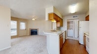 This single-floor residence offers a practical and comfortable layout designed for everyday living. The open-concept living and dining area is anchored by a tile-surround fireplace and finished with plush wall-to-wall carpeting, while a ceiling fan overhead and multiple windows allow natural light to fill the space with a bright, welcoming ambiance.

The kitchen is positioned centrally and features warm wood-toned cabinetry, white countertops, a peninsula with an under-mounted sink, and white appliances including a coil electric range and over-the-range microwave. A dedicated in-unit laundry area is conveniently accessible just off the kitchen.

The bedrooms are generously proportioned, each outfitted with soft carpeting, ceiling fans, and windows that invite natural light and exterior views. One bedroom includes a walk-in closet with built-in shelving, providing ample storage.

The residence includes two full bathrooms. One features a tub-shower combo with white subway tile surround accented by decorative tile at the top, paired with wood-look flooring and a wood-toned vanity. The second bathroom offers a standard tub-shower and matching wood-toned cabinetry. Textured ceilings are consistent throughout the home, adding a classic residential character to the overall aesthetic.