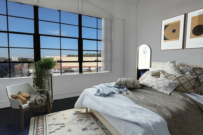 Factory window Bedroom With Tan bedding - Ford Factory Lofts