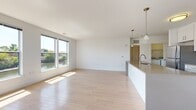 This well-appointed 2-bedroom, 2-bathroom residence at 21 Willett Ave in Port Chester, NY offers a thoughtfully designed open-concept layout with clean, modern finishes. The expansive living and dining area is anchored by light-toned hardwood flooring and large windows that invite abundant natural light and frame picturesque waterfront views. The kitchen is a standout feature, equipped with white shaker cabinetry, subway tile backsplash, stainless steel appliances including a gas range, microwave, and refrigerator, and a generous island with a quartz-style countertop and undermount sink — ideal for both cooking and casual dining. Pendant lighting adds a refined touch overhead. Both bedrooms are carpeted for comfort, with large windows providing natural light and outdoor views. The primary bedroom includes a sliding glass door leading to a private balcony. The two bathrooms are finished in a clean, contemporary style — one features a soaking tub with subway tile surround, mirrored medicine cabinet, and white vanity, while the second offers similar refined finishes with tile flooring. The overall aesthetic throughout is bright, neutral, and modern, creating a versatile and inviting living environment.