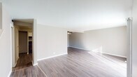 This two-story home in Woodridge, Illinois offers a clean, neutral aesthetic across both levels. The main floor features an open living area with wood-style laminate flooring and a ceiling fan, allowing natural light to stream across the space. A separate room with darker hardwood-style floors and a large sliding glass door with vertical blinds provides direct views of the outdoors and easy access to the exterior, with a staircase nearby leading to the upper level.

The kitchen is fitted with white shaker-style cabinetry, granite countertops, a stainless steel sink, and black appliances including a gas range with overhead ventilation. A bathroom on the main level includes a white vanity, toilet, and tub with tiled surround, accented by chrome hardware.

Upstairs, the bedrooms are carpeted in neutral gray tones, offering a softer feel. Each room receives natural light through windows, maintaining the home's bright and airy character. A second bathroom upstairs echoes the clean, simple design with chrome towel bars and neutral wall tones. Throughout both floors, the consistent use of warm neutrals and updated finishes creates a cohesive, move-in-ready environment.