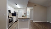 Located at 3978 75th St W in Bradenton, Florida, this single-floor residence offers a well-designed layout with a cohesive blend of comfort and functionality. The open living area is highlighted by rich, dark wood-look flooring, vaulted ceilings, a ceiling fan, and a textured finish overhead. A sliding glass door with vertical blinds floods the space with natural light and provides views of lush greenery outside.

The kitchen is thoughtfully appointed with white cabinetry, granite countertops, a peninsula with a built-in sink, and a full suite of stainless steel appliances including a refrigerator, range, and microwave. The kitchen flows seamlessly into the main living and dining areas, making the layout ideal for everyday living.

The bedrooms feature plush carpet flooring, neutral wall tones, and access to walk-in closets with built-in shelving. Natural light enters through windows framing outdoor tropical foliage, reinforcing the Florida setting. Both bathrooms are finished with wood-look flooring, white cabinetry, granite vanity tops, and tub-shower combinations with tile surrounds and brushed nickel hardware.

Throughout the home, consistent neutral tones, clean lines, and practical finishes create a bright, move-in-ready environment suited to a variety of lifestyles.