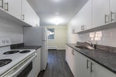 Located at 53 McMurchy Ave N in Brampton, Ontario, this 2-bedroom, 1-bathroom unit offers a practical and well-appointed layout across a single floor. The open-concept living and dining area is bright and welcoming, featuring grey laminate flooring, warm neutral walls, and large sliding doors that invite natural light and provide outdoor views of surrounding greenery. Baseboard heating is present throughout, ensuring year-round comfort.

The galley-style kitchen is efficiently designed with crisp white cabinetry, grey stone-finish countertops, a stainless steel sink, and white appliances including a stove and refrigerator. Upper and lower cabinets provide ample storage, and the layout flows conveniently toward the unit's entrance.

Both bedrooms are comfortably sized, finished with the same laminate flooring and soft neutral tones. The primary bedroom benefits from a window overlooking mature trees, creating a calm, natural outlook. The second bedroom is equally well-lit and offers a clean, move-in ready finish.

The full bathroom features white tile flooring, a full-size soaker tub with warm-toned tile surround, a vanity, and a toilet — all in a clean, functional arrangement. Overall, the unit presents a fresh, updated interior suitable for comfortable everyday living.