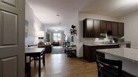 This well-designed 3-bedroom, 2-bathroom single-floor unit offers a functional and cohesive layout ideal for shared or family living. The open-concept living and dining area flows seamlessly from the kitchen, creating a connected and spacious feel. Warm wood-style flooring runs throughout the main living spaces, complementing the neutral wall tones and creating a welcoming ambiance.

The kitchen is a standout feature, equipped with rich dark espresso cabinetry, granite-style countertops, stainless steel appliances including a refrigerator and range, and ample storage. A dedicated laundry area with a washer and dryer is conveniently accessible from the kitchen.

The living room is generously proportioned with high ceilings that enhance the sense of openness, and a ceiling fan adds comfort. Natural light filters in through windows at the far end of the room, brightening the entire open-plan space.

The primary bedroom is a comfortable retreat, featuring large windows with views, plush carpeting, and a dedicated closet with hanging storage. The two full bathrooms each include a tub/shower combination with tiled surrounds, wood-style flooring, and wall-mounted shelving for added storage convenience.

Additional bedrooms offer carpeted floors, closet space, and natural light, making each room practical and inviting. Overall, this unit delivers a balanced blend of functionality and modern design.