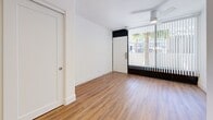 Located at 5121 E La Puente Ave in Phoenix, AZ, this efficiently designed single-floor unit offers a thoughtfully organized layout across a compact footprint. Warm wood-look flooring runs consistently throughout the space, lending a cohesive and inviting feel to every room.

The main living area is bright and open, benefiting from a large floor-to-ceiling window dressed with vertical blinds that allow natural light to filter in while offering views of outdoor greenery. A ceiling fan overhead provides practical comfort in the Arizona climate.

The kitchen is modern and well-appointed, featuring stainless steel appliances including a range with oven, over-the-range microwave, dishwasher, and refrigerator. Gray cabinetry with clean-lined hardware offers ample storage above and below the counter, while a white tile backsplash and recessed lighting add a polished, contemporary touch. A single-basin sink sits neatly beneath the upper cabinets.

The bathroom is clean and functional, featuring a full tub-and-shower combo with built-in corner shelving and chrome fixtures. A bold navy accent wall provides a striking contrast to the white surround and bright white fixtures, creating a modern aesthetic. Wood-look flooring continues here, completing the unified design throughout the unit.