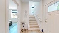 Located at 208 Park Lake Street, this contemporary three-story home offers 3 bedrooms and 4 bathrooms across a well-designed layout. The entry foyer welcomes you with light wood flooring, crisp white walls, and a staircase accented by natural light streaming through black-framed windows — a design detail that recurs throughout the home.

The main living floor hosts an open-concept kitchen and living room. The kitchen features white shaker cabinetry, stainless steel appliances, a large center island with a striking marble-look quartz countertop, and light hardwood flooring. The adjacent living room is bathed in natural light from oversized black-framed windows, creating an airy, welcoming atmosphere. A separate dining room offers an intimate setting with direct outdoor views.

The bathrooms are finished with elegant marble-look tile flooring and wall surrounds, white vanities, and glass-enclosed walk-in showers, lending a clean and refined aesthetic throughout.

The upper floors house the bedrooms, including a generously sized primary suite. Each bedroom features light hardwood floors, built-in closets, and ample natural light. The three-floor layout — with the ground floor serving as an entry and transition level — provides a clear sense of separation between living and sleeping spaces, making this home both functional and sophisticated.