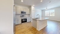 Located in San Antonio, TX along W Loop 1604 N, this one-bedroom, one-bathroom unit offers a well-designed single-floor layout with modern finishes throughout. The kitchen is a standout feature, centered around a large granite-topped island with an integrated sink, providing ample prep and dining space. Soft gray shaker-style cabinetry, a classic tile backsplash, and a full suite of stainless steel appliances — including a french door refrigerator, range, and over-the-range microwave — complete this functional and stylish space. Warm wood-look flooring runs continuously through the kitchen, living area, bedroom, and bathroom, creating a cohesive aesthetic. The bedroom is a comfortable size, offering a ceiling fan and a window with natural light and neighborhood views. The bathroom is well-appointed with a granite-topped vanity, gray shaker cabinetry with brushed nickel hardware, a large wall mirror, and a marble-tiled shower surround. A dedicated walk-in closet with wire shelving provides organized storage. Recessed lighting and crisp white walls lend the space a clean, contemporary feel throughout.