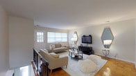 Located at Raritan Crossing, Building 1 #20, this single-floor residence offers a comfortable and thoughtfully laid-out living space. The living room serves as the heart of the home, featuring warm parquet hardwood flooring, neutral-toned walls, and generous natural light streaming through large windows fitted with layered blinds. The open, airy feel is complemented by a welcoming entry door with a glass panel. The kitchen is equipped with classic oak cabinetry, granite-style countertops, a double sink, dishwasher, and full-size refrigerator, with tile flooring and a window above the sink providing additional light. The primary bedroom is painted in a soft blue-gray palette, creating a serene retreat, and features parquet flooring and ample closet access. A second bedroom offers a clean, bright atmosphere with parquet flooring, a window, and a sliding closet. The full bathroom includes a tub-shower combination with warm-toned tile surround, a vanity with sink, and a window for ventilation. Throughout the residence, the consistent use of light tones and natural materials creates a cohesive, inviting ambiance suited for comfortable everyday living.