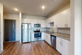 Located at 1905 Riverside Pkwy in Douglasville, Georgia, this single-story, 3-bedroom, 2-bathroom home offers a clean, modern aesthetic with a functional open-concept layout. The kitchen is a standout feature, showcasing crisp white cabinetry, granite countertops, a subway tile backsplash, and a full suite of stainless steel appliances including a refrigerator, range, microwave, and dishwasher. Rich hardwood-style flooring flows seamlessly through the kitchen and into the combined living area, which is filled with natural light from multiple windows and finished with a ceiling fan overhead. The spacious primary bedroom continues the hardwood-style flooring and features dual windows that bring in ample natural light, along with a ceiling fan. The two additional bedrooms are carpeted and each include a ceiling fan and window with outdoor views, providing comfortable and versatile spaces. Both bathrooms are well-designed — one features a soaking tub with a tiled surround and built-in shelving, while the second includes a tub/shower combination, a vanity, and hardwood-style flooring. A hallway and closet round out the layout, adding practical storage. The overall ambiance is bright, clean, and move-in ready.