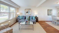 This two-story, 2-bedroom, 1-bathroom home offers a thoughtfully arranged layout that balances functionality with a warm, inviting aesthetic. The main level features rich hardwood flooring throughout the living, dining, and kitchen areas. The living room is bright and airy, with windows that bring in natural light and provide views of the surrounding greenery, complemented by clean white walls and crown molding details. Adjacent to the living space, the dining area accommodates a round dining table and is framed by additional windows, enhancing the open feel of the floor. The kitchen is well-equipped with granite countertops, warm wood cabinetry, stainless steel appliances including a gas range and dishwasher, and additional pantry storage. Upstairs, the two bedrooms are carpeted and generously proportioned. The primary bedroom features a bank of windows that flood the room with natural light and offer pleasant outdoor views, creating a serene retreat. The full bathroom is finished with tile flooring, a granite-topped vanity with dark wood cabinetry, and a shower/tub combination, accented by a natural light source from a window. A staircase with a classic wood railing connects the two levels, completing this comfortable and practical home.