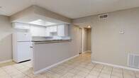 Located at 6212 S Dale Mabry Hwy in Tampa, Florida, this single-story unit offers a practical and well-organized layout with a clean, neutral aesthetic throughout. The open-concept living and dining area features light ceramic tile flooring and flows seamlessly into a peninsula-style kitchen. The kitchen is outfitted with white cabinetry, granite-look countertops, a breakfast bar, a full suite of white appliances including a refrigerator and range, and a skylight above that brings in natural light. A dedicated living space features wood-look laminate flooring, vertical blinds on a large window, and a textured ceiling, providing a bright and airy atmosphere. The bedrooms continue the laminate flooring theme, with each room offering closet storage — one featuring a ceiling fan and direct access to a hallway. A full bathroom includes a tiled tub-shower combination and wood-look flooring, finished in clean whites throughout. A separate entry area with tile flooring and a large window rounds out the unit's functional design. The neutral gray and beige tones throughout create a cohesive, move-in-ready environment suited for a variety of living arrangements.