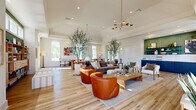 Located at 729 Crescent Woods Dr in Gahanna, Ohio, this single-floor space offers a thoughtfully designed, open-concept layout that maximizes both functionality and aesthetic appeal. The interior is anchored by wide-plank hardwood flooring that runs throughout, creating a warm and cohesive foundation across every zone.

The expansive main living area features soaring ceilings with elegant tray detailing and is bathed in natural light from an abundance of large double-hung windows. A dramatic floor-to-ceiling dark tile fireplace serves as a striking focal point, flanked by curated seating arrangements that include plush sofas, modern accent chairs in rich cognac leather, and layered area rugs. Tall potted olive trees lend a biophilic warmth to the space, softening the architectural lines.

A dedicated dining area accommodates a solid wood communal table with mixed cane-back and upholstered seating, illuminated by a sculptural brass sputnik chandelier overhead. Glass-paned French doors connect to an adjacent room, enhancing the flow and openness of the layout. A built-in shelving wall with teal-painted backing provides generous display and storage space. Recessed lighting throughout complements the abundant natural light, ensuring the space remains bright and inviting at all hours.