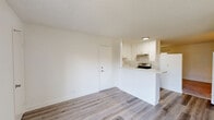 Located at 200 Orchard Pl in Oxnard, CA, this efficiently designed one-bedroom, one-bathroom residence makes excellent use of its compact footprint. The open-concept living and kitchen area serves as the heart of the unit, featuring light wood-style laminate flooring and bright white walls that create a clean, airy atmosphere. A textured ceiling runs throughout the main living space, adding subtle character. The peninsula-style kitchen is positioned along one wall, offering white cabinetry, a range with overhead ventilation, and a breakfast bar counter that opens seamlessly into the living area. A sliding glass door in the living room allows natural light to pour in and provides access to the outdoors. The bedroom is a comfortable, well-proportioned space finished with plush carpet flooring. It features a window overlooking the surrounding neighborhood and a mirrored sliding-door closet that adds both storage and a sense of depth to the room. The bathroom is straightforward and functional, complete with a full-size soaking tub and shower combination, a toilet, and wood-style flooring that coordinates with the main living area. The overall palette of neutral whites and warm beige tones throughout the unit lends a clean and versatile canvas suitable for a variety of personal styles.
