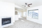 Located in Draper, Utah, this single-floor, 3-bedroom, 2-bathroom home offers a well-designed layout with comfortable living spaces throughout. The living room serves as the heart of the home, featuring a tile-surround fireplace, vaulted ceilings, and a ceiling fan, all bathed in natural light from multiple windows that offer views of the surrounding neighborhood. A breakfast bar connects the living area to the galley-style kitchen, which is equipped with white cabinetry, ample counter space, tile flooring, and a full suite of white appliances including a range, microwave, dishwasher, and refrigerator. The primary bedroom is generously sized, with vaulted ceilings, a ceiling fan, and a large window providing outdoor views. The two additional bedrooms feature plush carpeting — one highlighted by an elegant arched window that floods the room with natural light, and another with a standard window and built-in overhead shelving detail. Both bathrooms are finished with stone-look tile flooring, tub-shower combinations with tiled surrounds accented by a decorative border, and vanities with counter space. Soft carpet runs through the living areas and bedrooms, while tile flooring is found in the kitchen and bathrooms, creating a cohesive and functional interior.